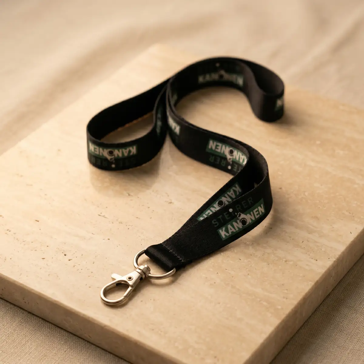 Steierkanonen Lanyard in Schwarz auf einer hellen Steinplatte